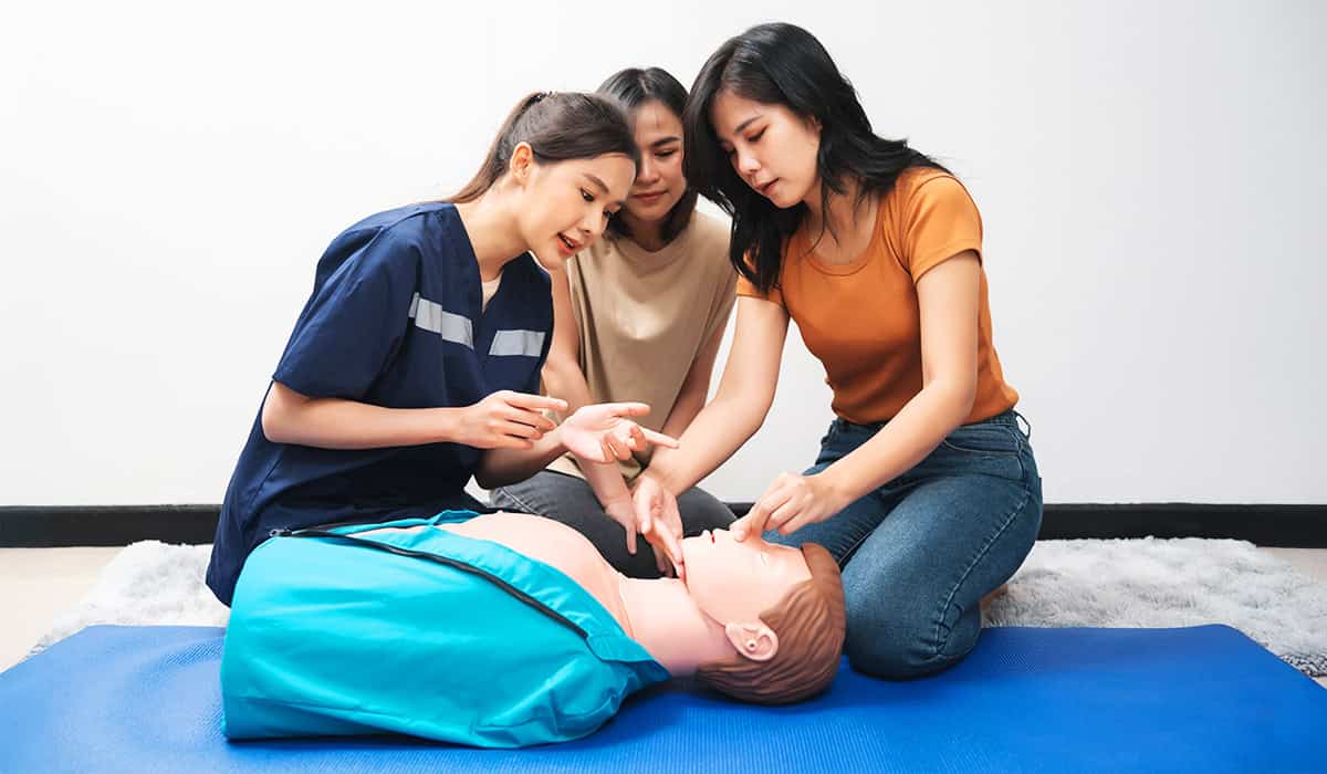 Someone being taught to administer rescue breaths