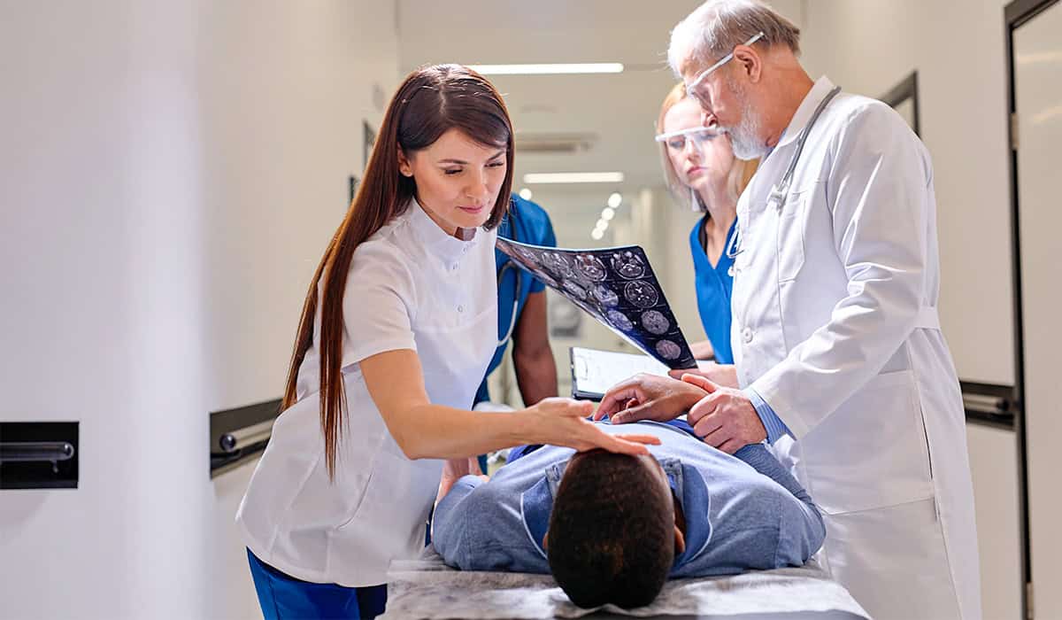 An image of a patient and their doctors who are examining the results of a CT scan